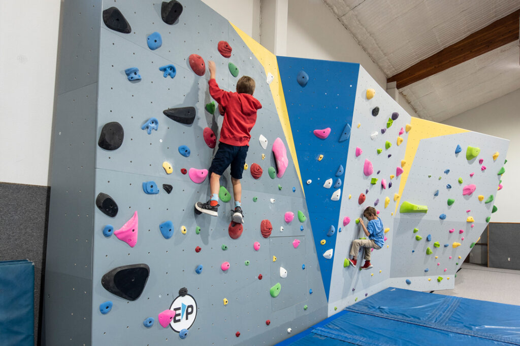 two children climbing on an indoor climbing wall